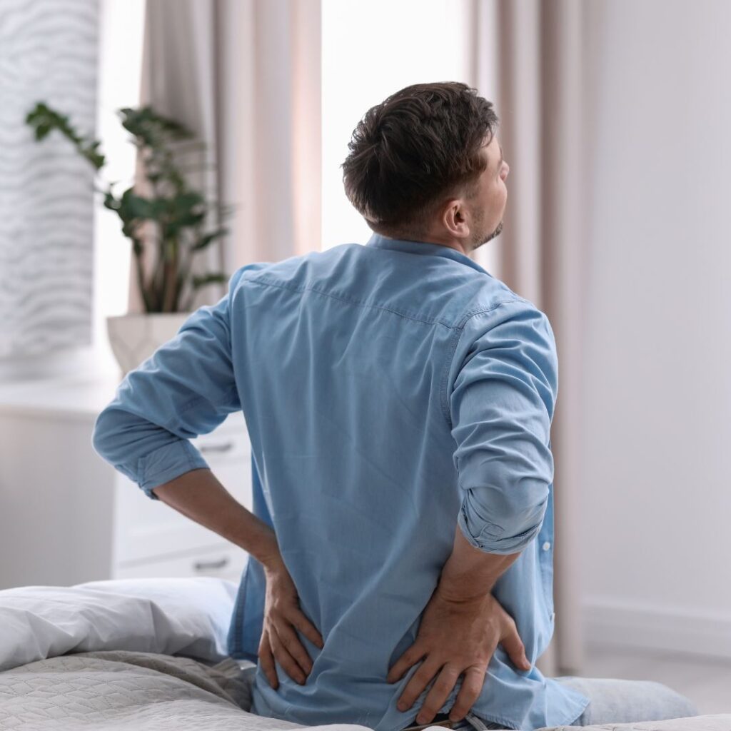 stretching lower back, sitting on edge of bed